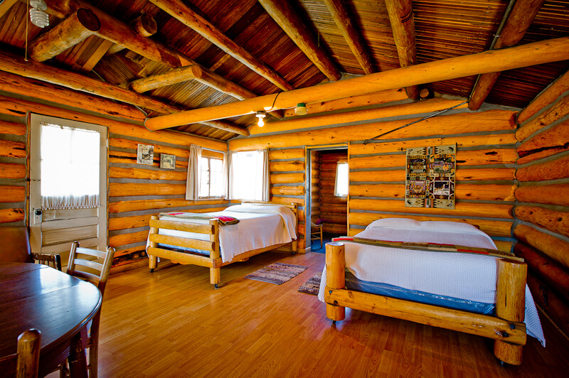 Two white beds in a wooden cabin