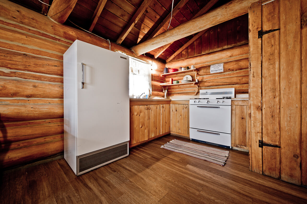 Wooden cabin with a white refrigerator and a stove